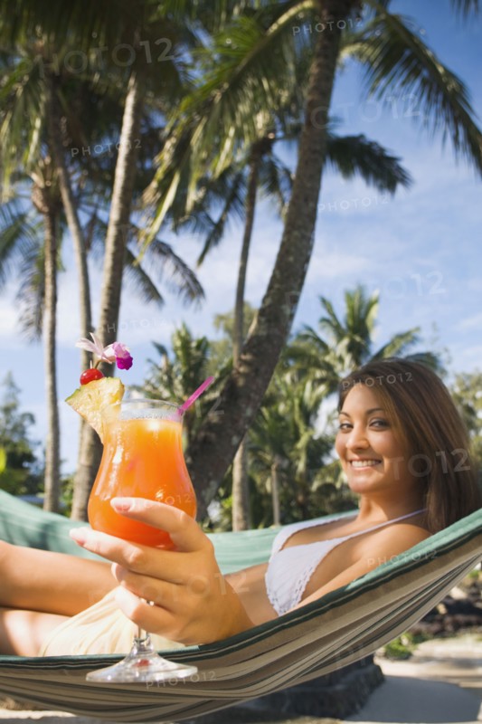 Asian woman with cocktail in hammock