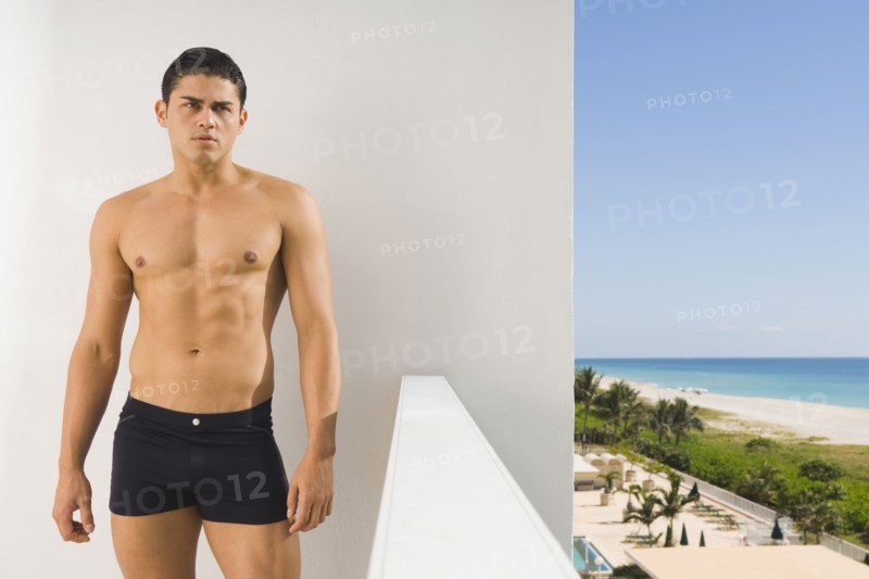 Hispanic man in bathing suit on balcony