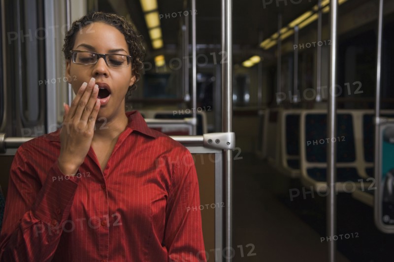 African businesswoman yawning on train