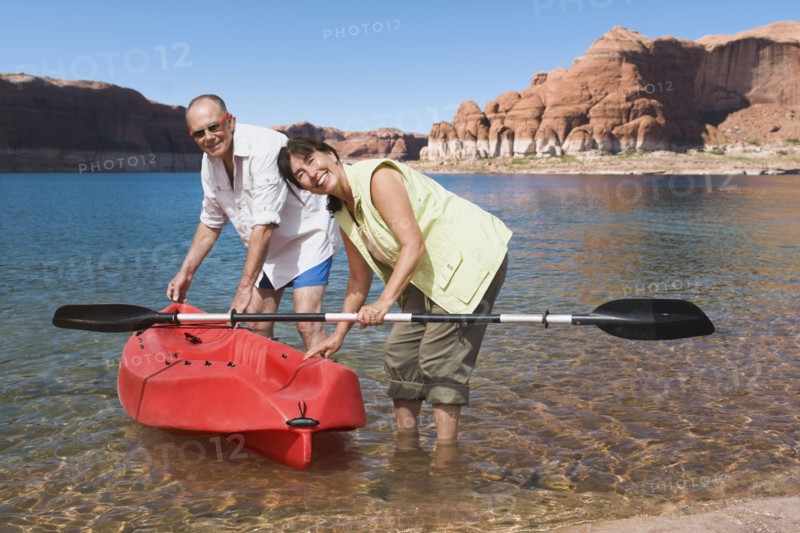 Multi-ethnic senior couple next to kayak in water