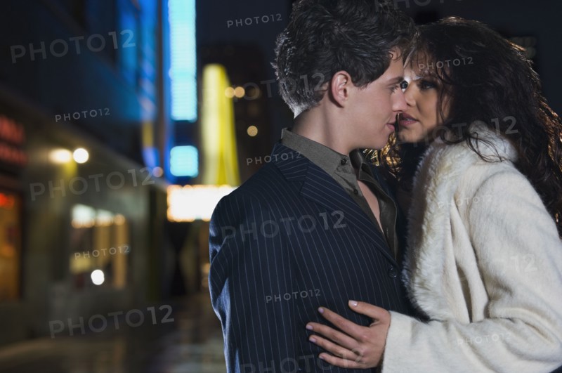 Elegant couple kissing on urban street at night