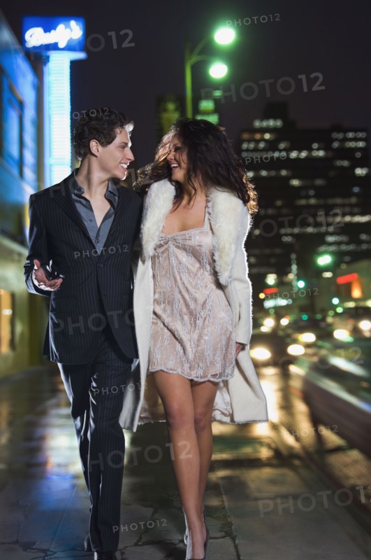 Multi-ethnic couple in formal attire walking down sidewalk