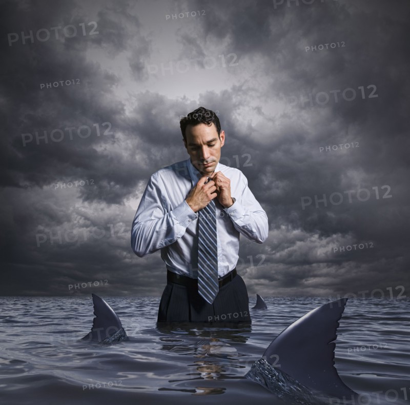 Latin businessman standing in shark infested waters