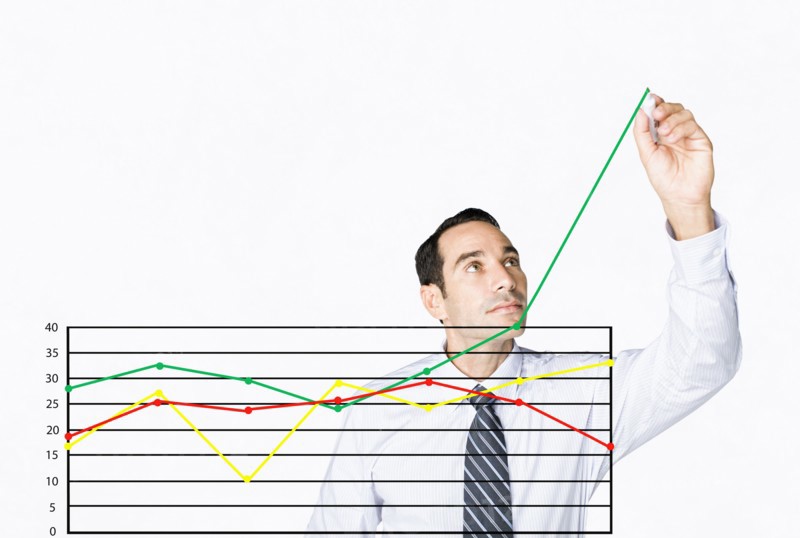 Hispanic businessman drawing chart on clear board