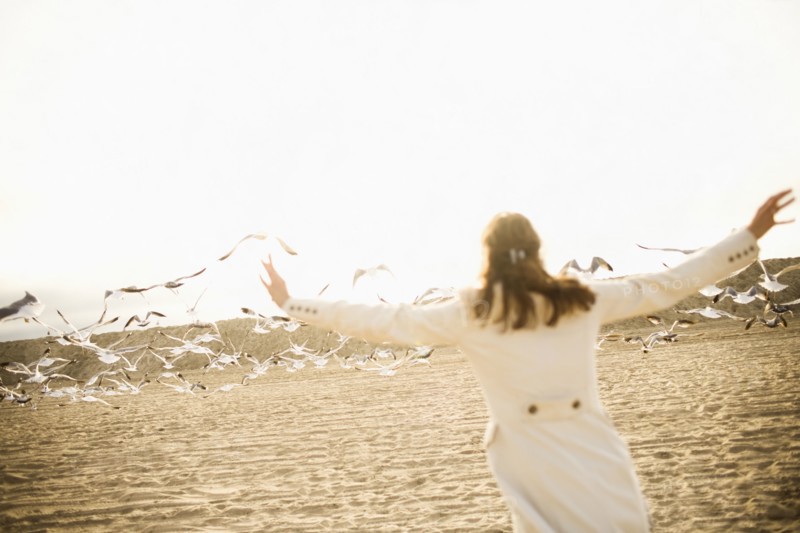 Woman scaring seagulls on beach