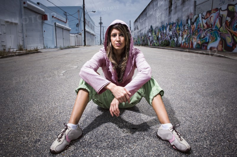 Hispanic woman sitting in alley with graffiti