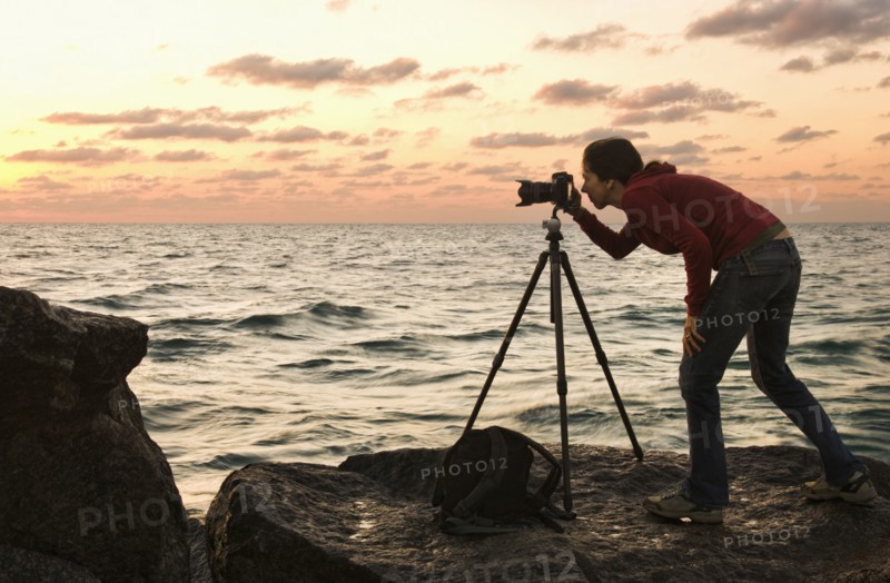 Mixed race woman using camera near ocean