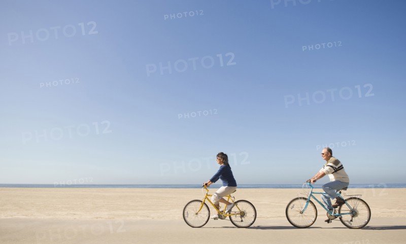Couple riding bicycles on beach