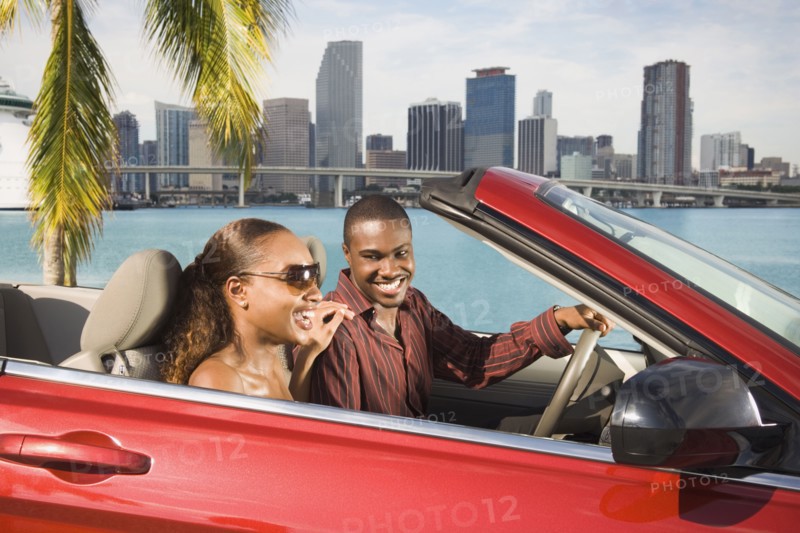African American couple driving in convertible
