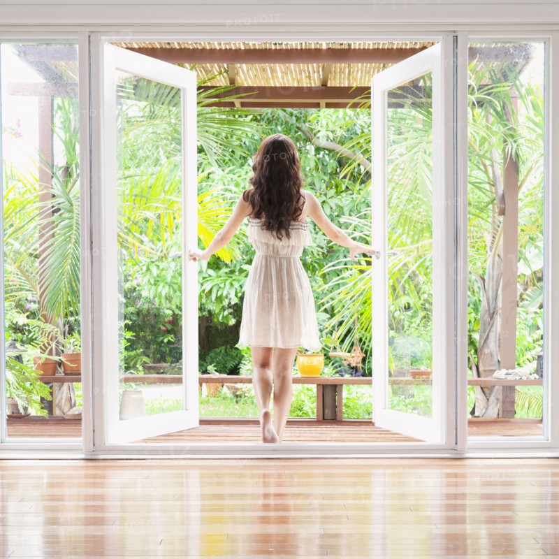 Hispanic woman opening French doors to patio