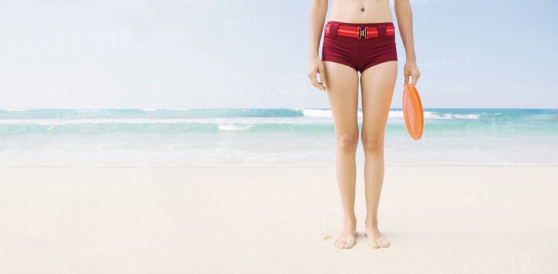 Caucasian woman holding plastic disc on beach