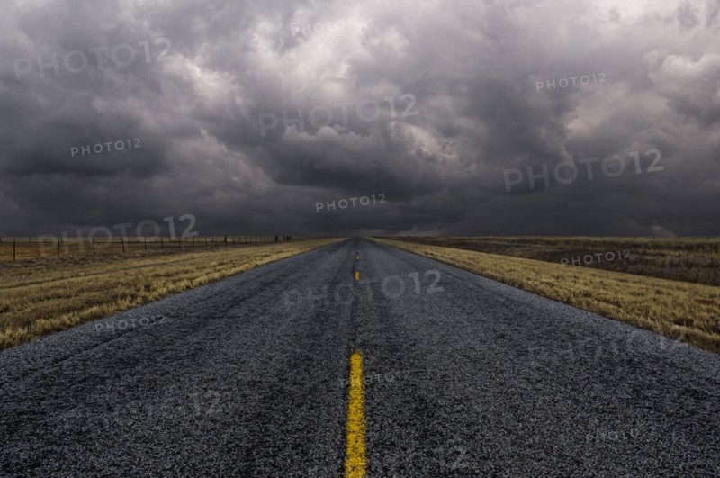 Paved road under cloudy sky in remote landscape