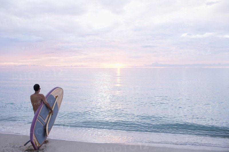 Caucasian surfer holding paddleboard on beach