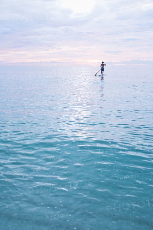 Caucasian man standing on paddleboard in ocean