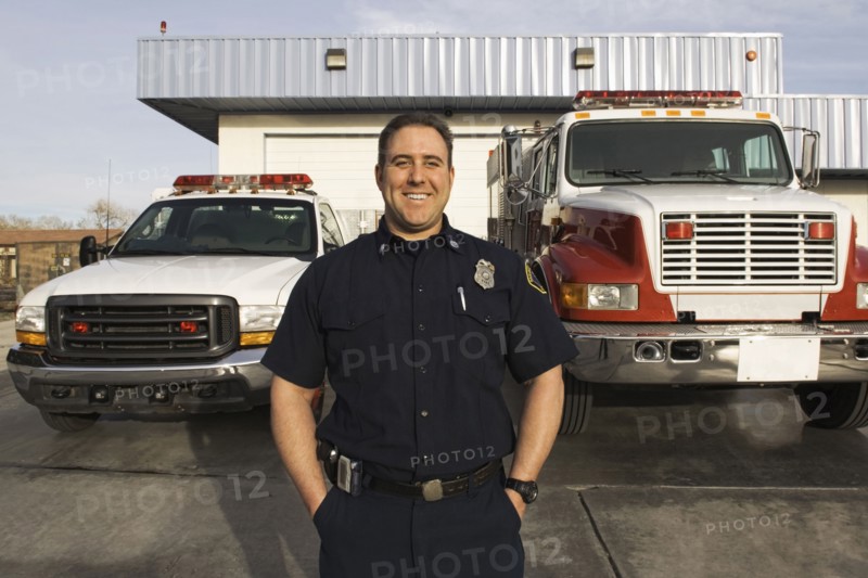 Caucasian firefighter smiling near fire trucks