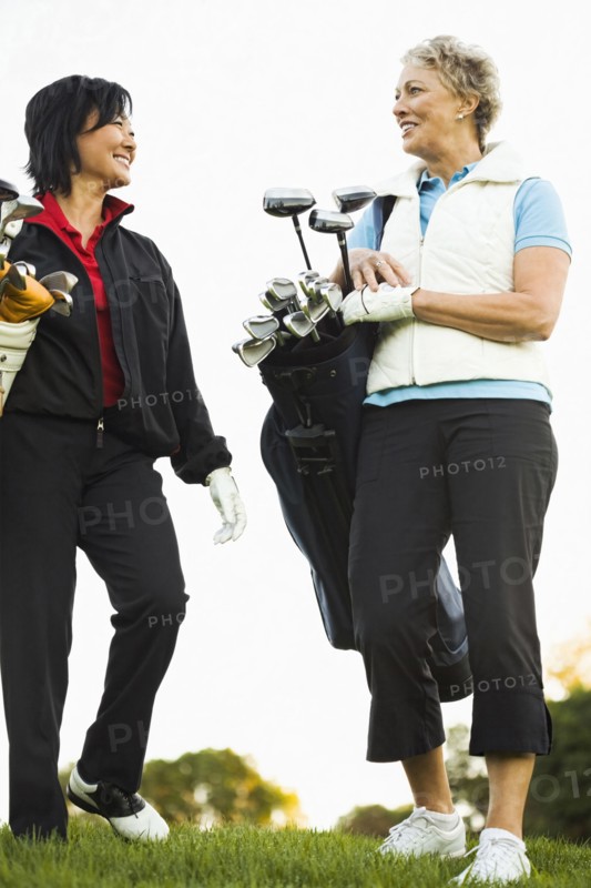 Women carrying golf clubs on golf course
