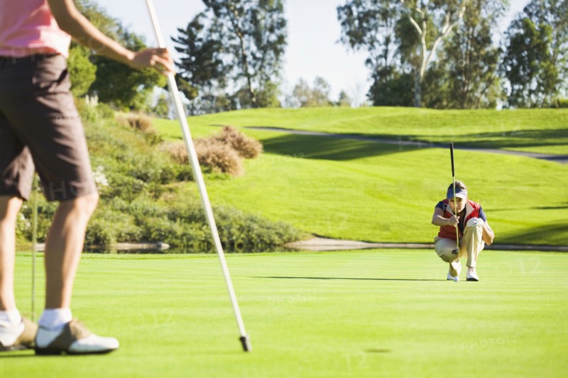 Women planning putt on green at golf course