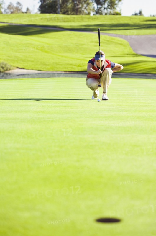 Caucasian woman planning putt on green at golf course