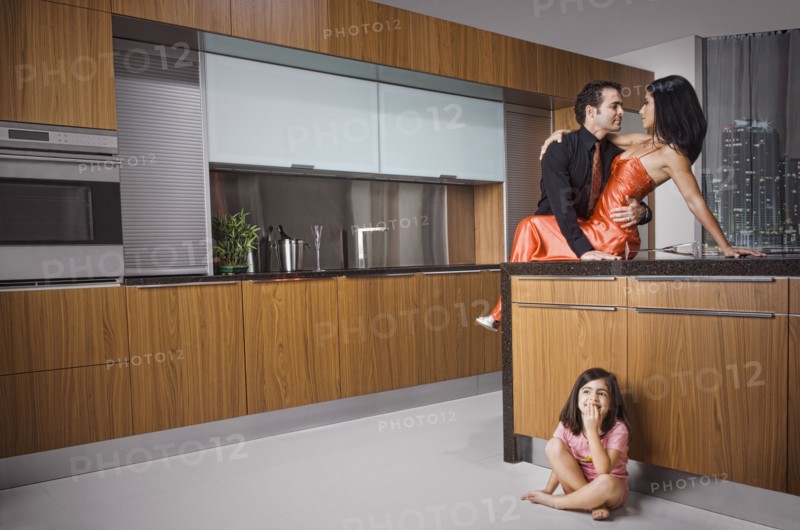 Caucasian girl eavesdropping on parents in kitchen