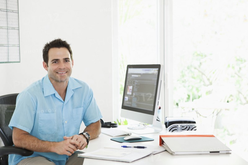 Portrait of Mixed Race man sitting at desk in home office