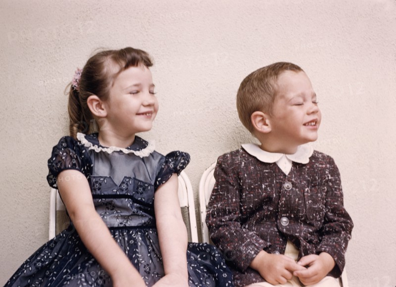 Caucasian brother and sister smiling with eyes closed