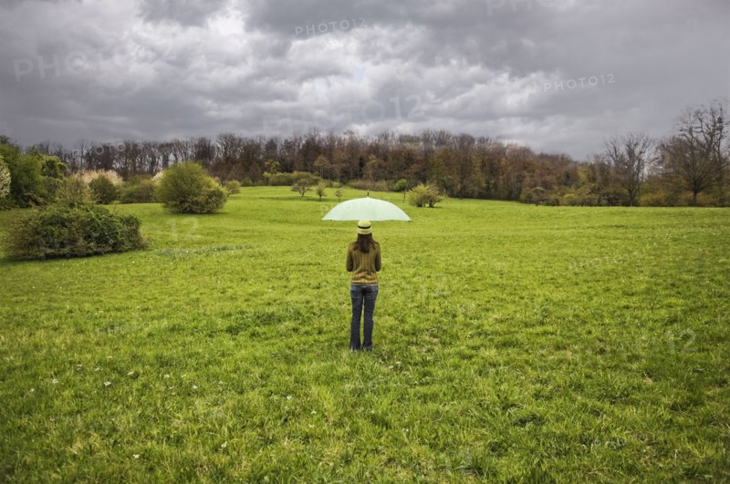 Mixed Race holding umbrella in field