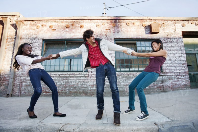 Women pulling on male friend's arms