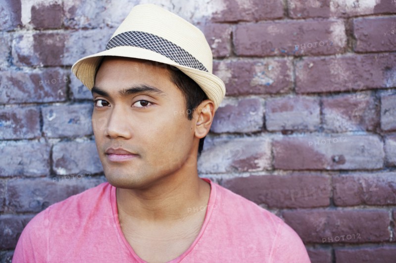 Serious Asian man near brick wall