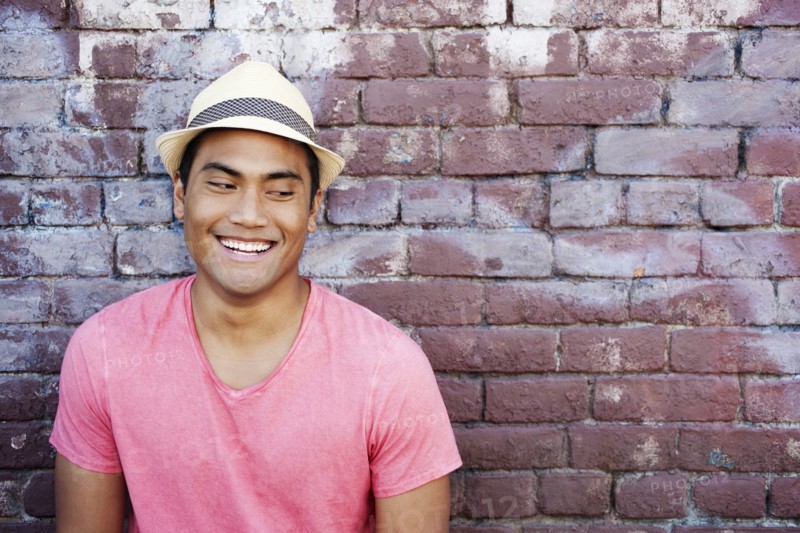 Smiling Asian man near brick wall