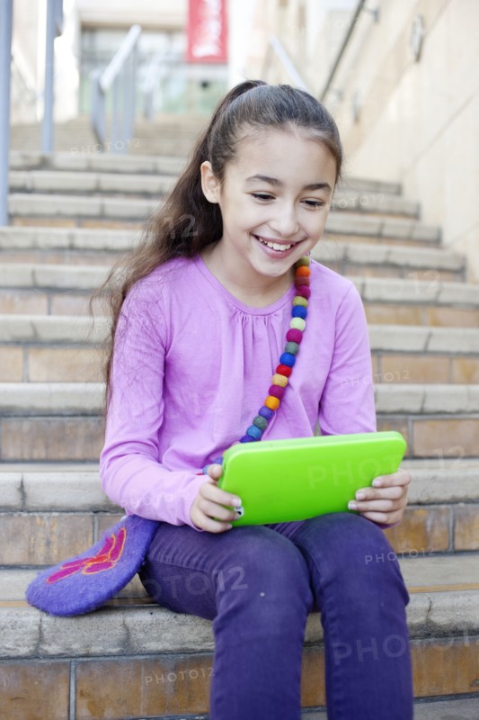 Mixed race girl using digital tablet on staircase