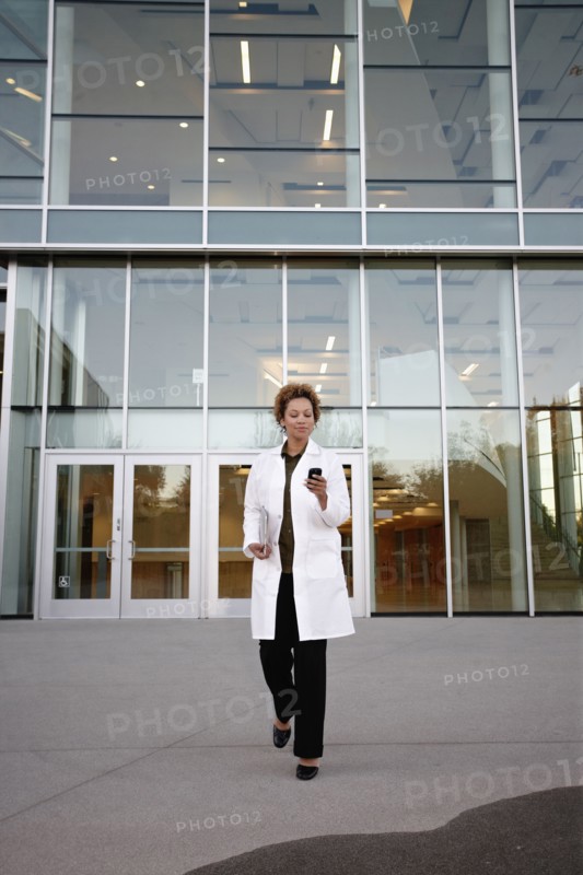 Doctor walking and text messaging on cell phone