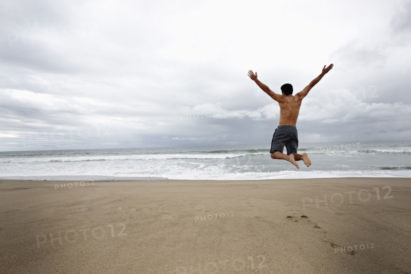Young man jumping for joy on beach