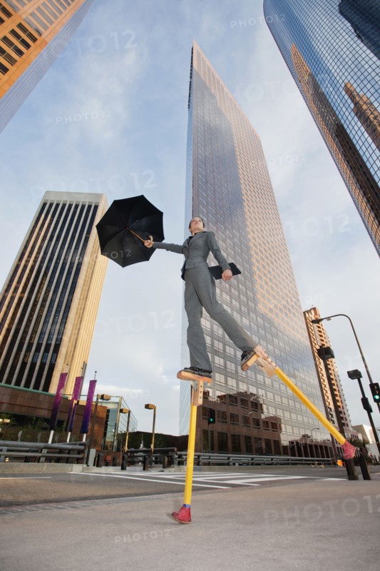 Caucasian businesswoman walking on stilts in urban environment
