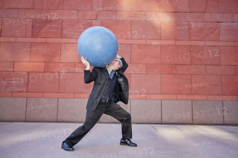 Caucasian businessman carrying heavy ball