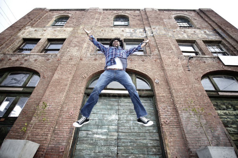 Black man jumping next to urban building