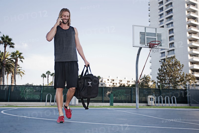 Caucasian man on basketball court talking on cell phone