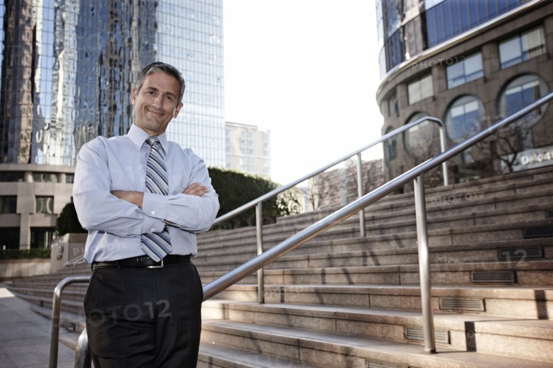 Hispanic businessman standing outdoors with arms crossed