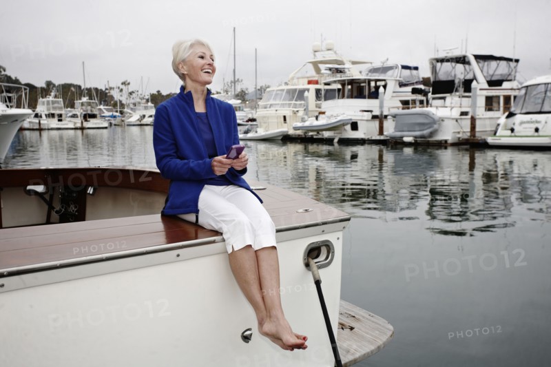 Woman sitting on boat text messaging on cell phone