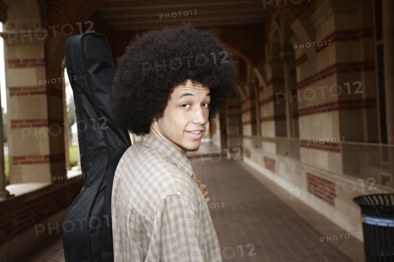 Man with afro carrying guitar in case