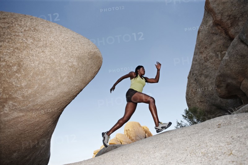 Woman running up boulder in remote area