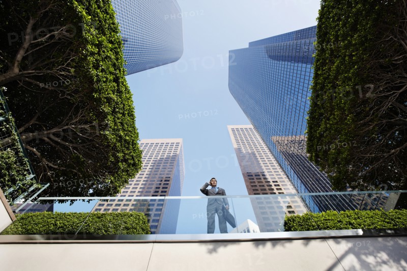 Businessman standing on balcony talking on cell phone