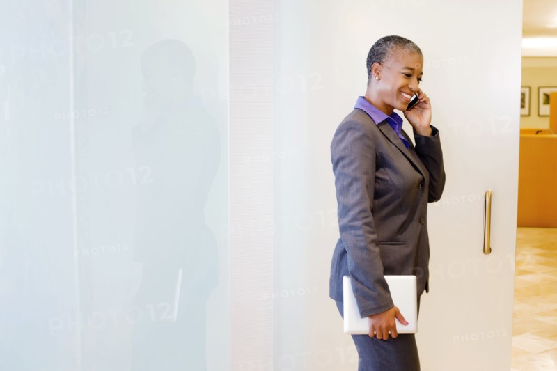 Black businesswoman holding digital tablet and using cell phone