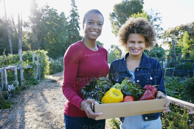 Mother and daughter gathering vegetables in community garden