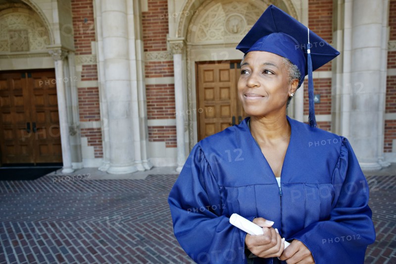 Smiling Black woman holding graduation diploma