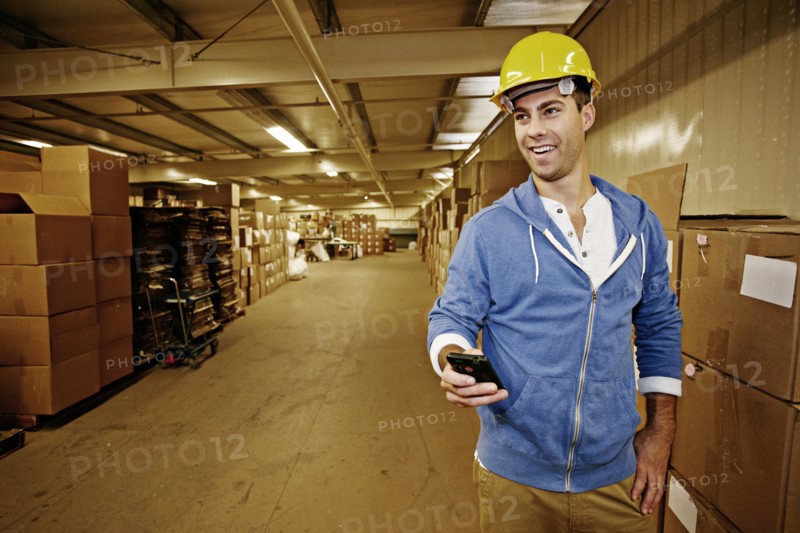 Caucasian worker using cell phone in warehouse