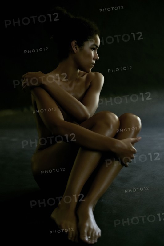 Nude mixed race woman covering her body