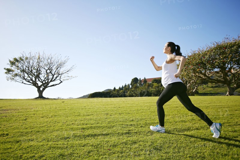 Pregnant mixed race woman jogging in field