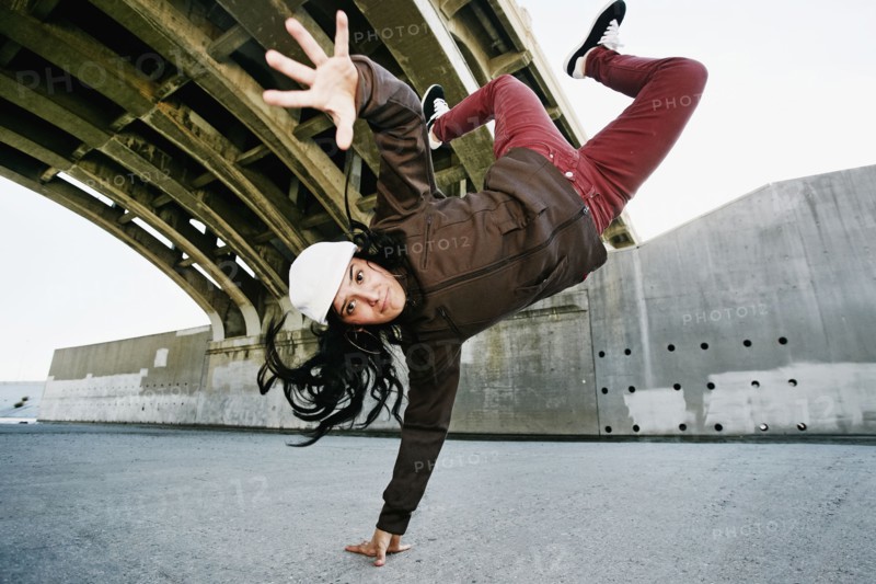 Hispanic woman break dancing under overpass