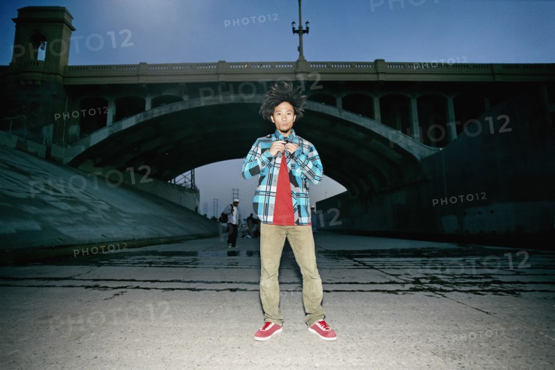 Asian man standing under overpass