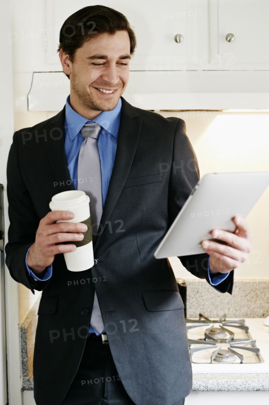 Caucasian businessman using tablet computer in kitchen